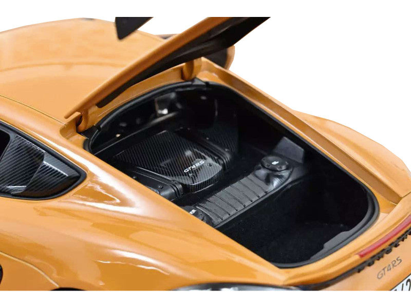 Open hood of a yellow sports car with carbon fiber components.