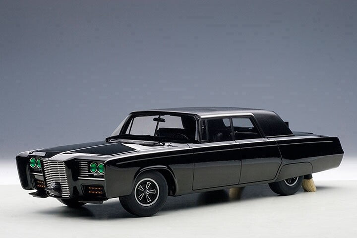 Black Diecast Model car with green headlights on a gray background