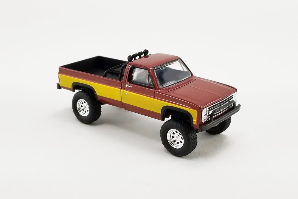 Model truck with a maroon body and yellow bed on a white background