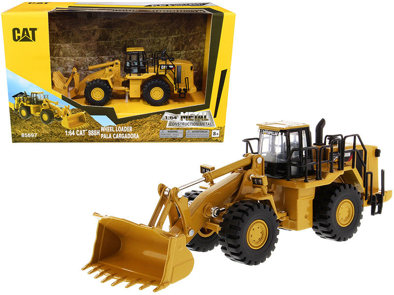 Toy wheel loader in front of its packaging with 'Caterpillar' branding.