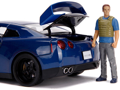 Blue sports car with open trunk and a figure standing next to it on a white background
