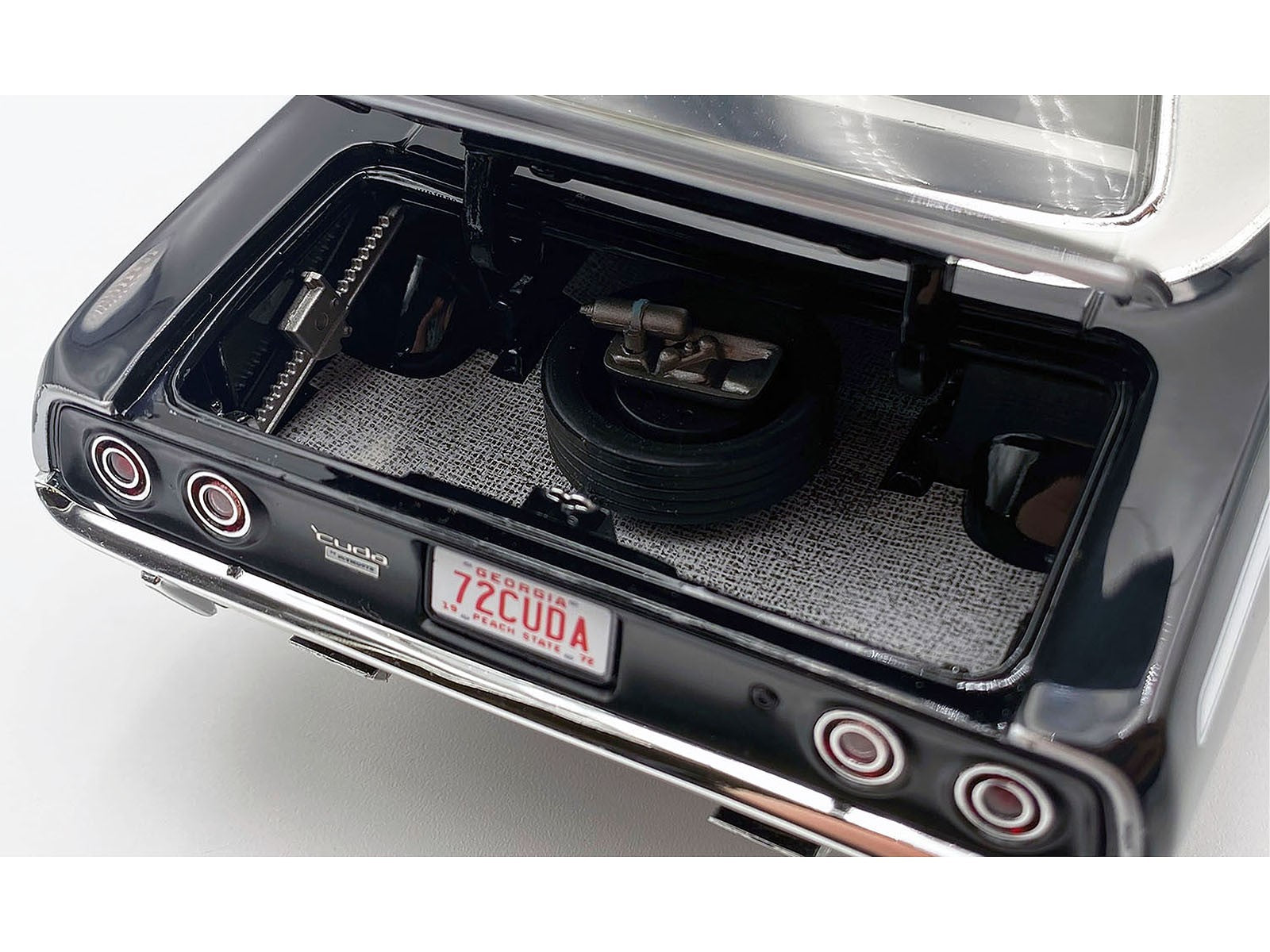Close-up of a car's exhaust system with a 'ZCuda' license plate on a white background