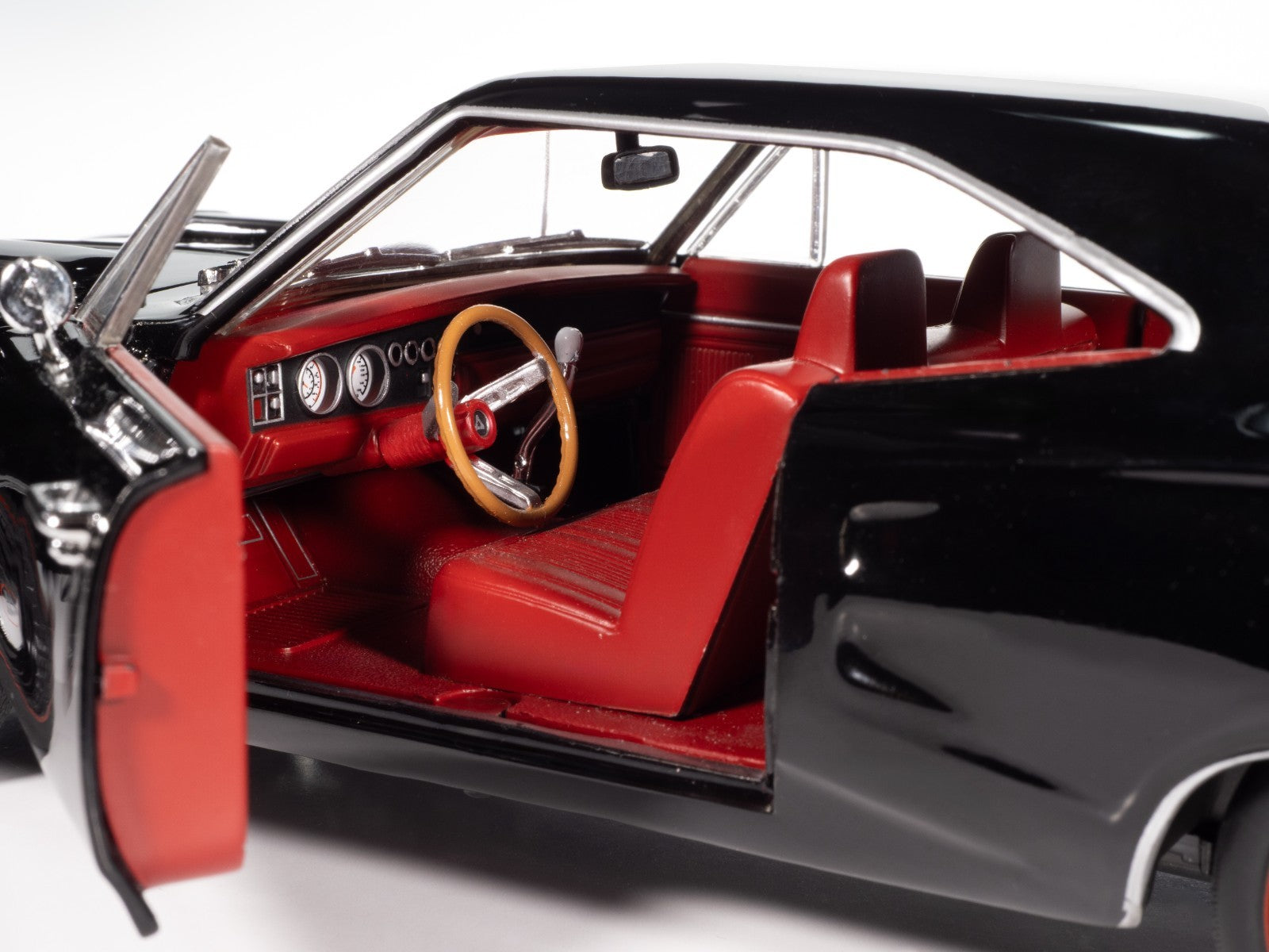 Close-up of a classic car's interior with red seats and black dashboard.