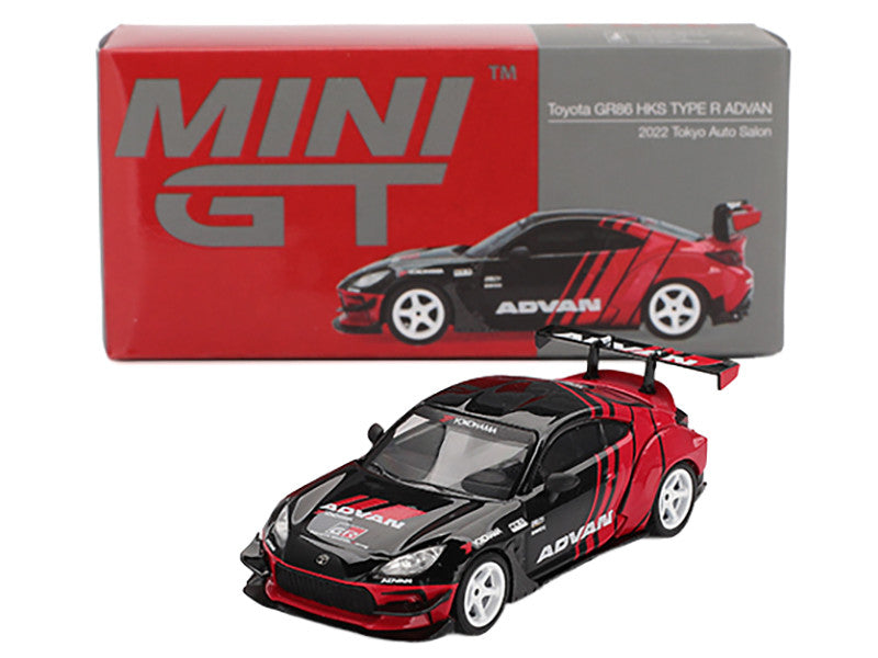 Red and black toy car with 'Mini GT' branding and a visible box in the background.