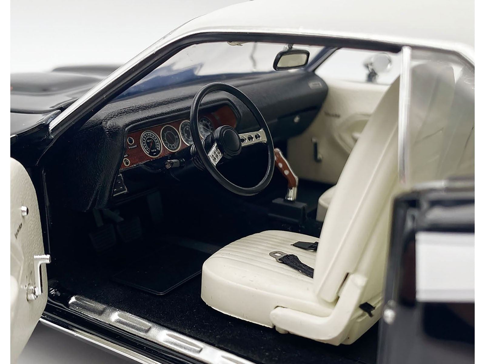 Close-up of a classic car's interior with white seats and black dashboard.