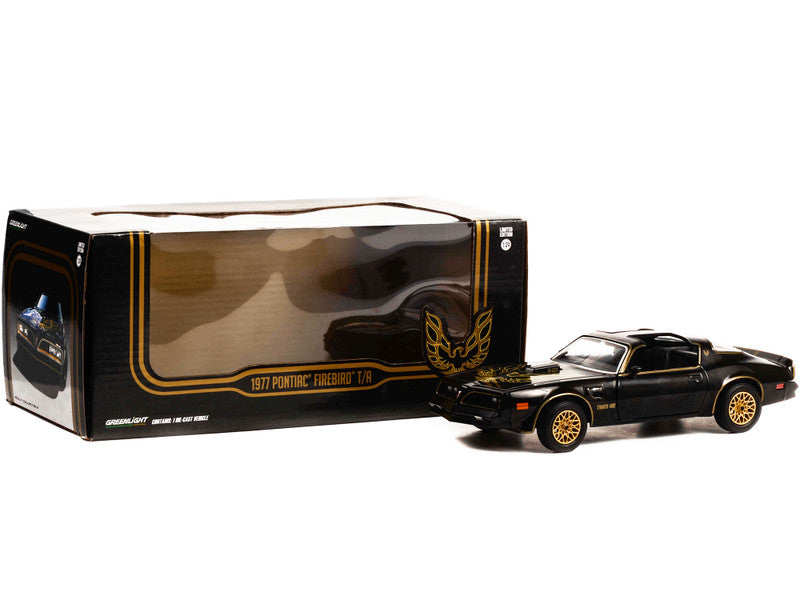 Black and gold model car next to its packaging on a white background