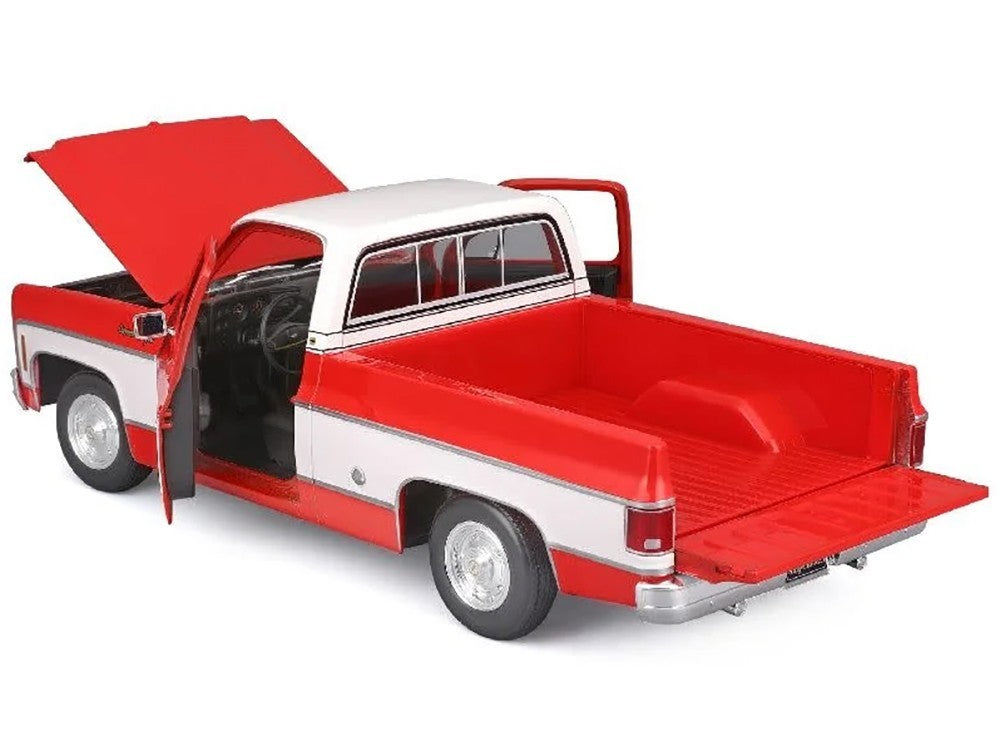 Model of a red and white pickup truck with open doors and hood on a white background