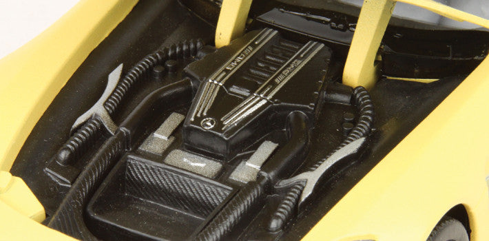 Close-up of a car's engine bay with visible branding on a yellow car.