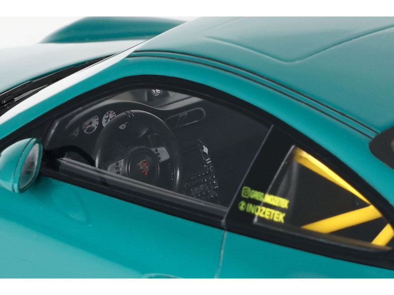 Close-up of a teal sports car with visible branding on the side.
