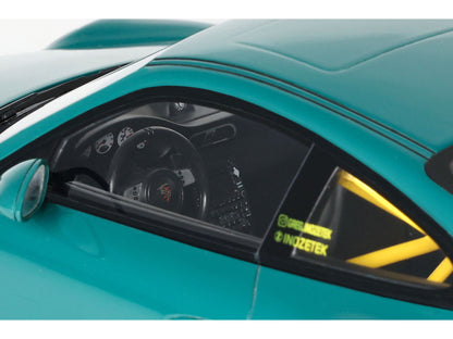 Close-up of a teal sports car with visible branding on the side.