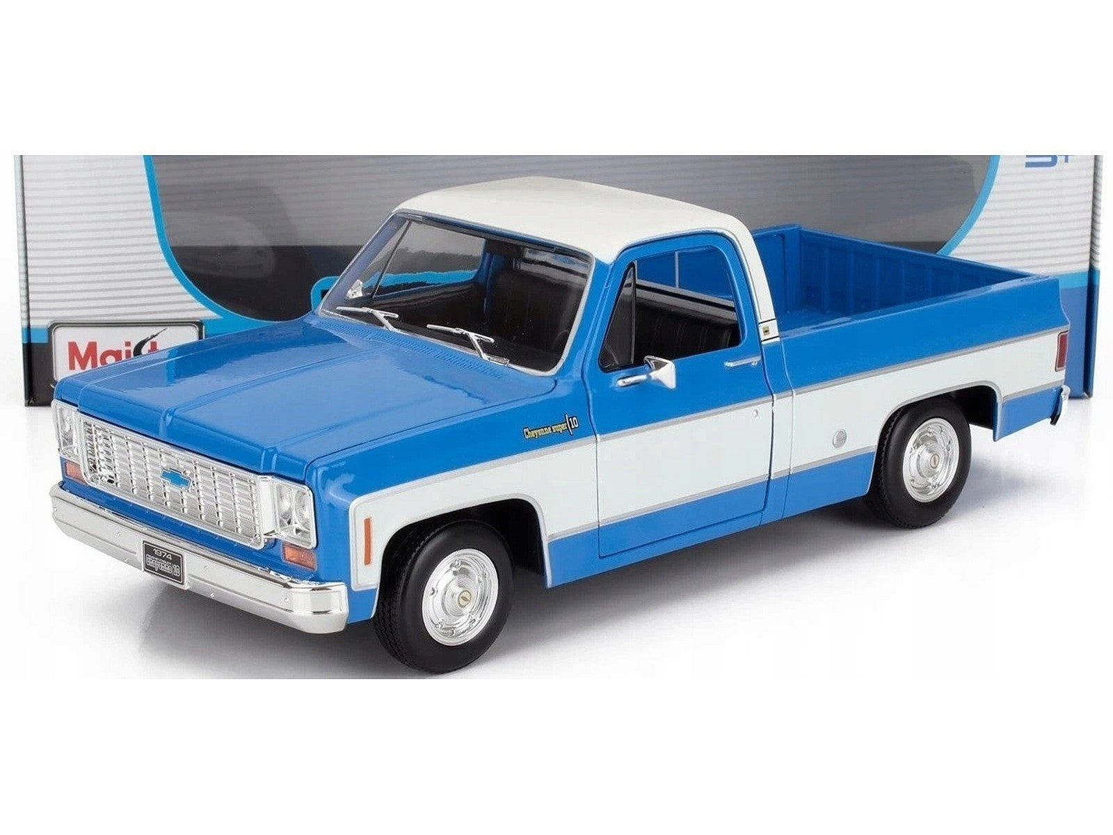 Model of a blue and white pickup truck in front of a garage door.