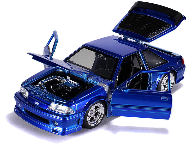 Blue model car with open doors and hood on a white background