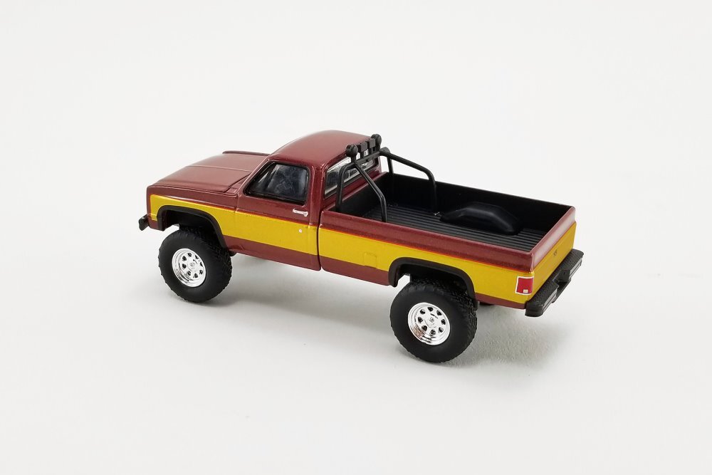 Model truck with a maroon and yellow color scheme on a white background
