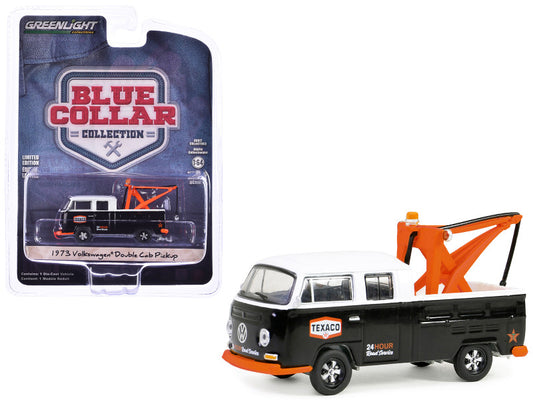 A 1/64 scale diecast model of a 1973 Volkswagen Double Cab Tow Truck, predominantly black and white, with orange crane accents, from the 'Blue Collar Collection' series, packaged in a blister pack with blue and white product card.