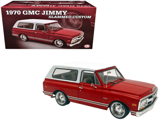 A red 1970 GMC Jimmy Slammed Custom die cast model car is displayed with its original box in the background. The model has white top, detailed chassis, and is steerable.