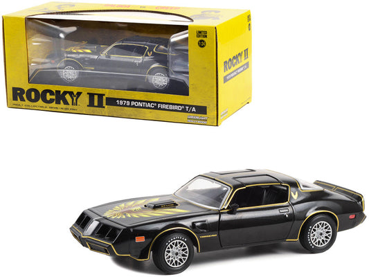 A 1/24 scale diecast model of a 1979 Pontiac Firebird Trans Am in black color with hood, packaged in a yellow box labeled 'Rocky II'.