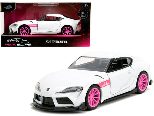 A diecast model of a 2020 Toyota Supra in white with pink wheels, presented in its packaging.