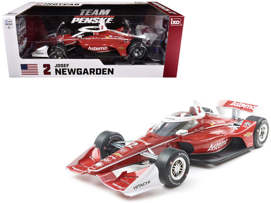 A diecast model of a red and white Dallara IndyCar with the number 2 and the name 'Newgarden' on the side, along with the 'Astemo' sponsor logo, in its original packaging.