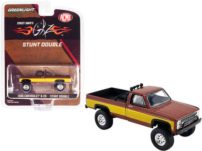 A diecast model of a 1986 Chevrolet K-20 Pickup Truck in brown with gold stripes, packaged in a blister pack with 'Stunt Double' and Fall Guy Tribute graphics.