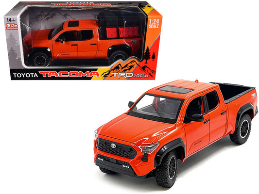 A diecast model of a 2024 Toyota Tacoma TRD Off-Road Edition Pickup Truck in Octane Orange with a bed camper.