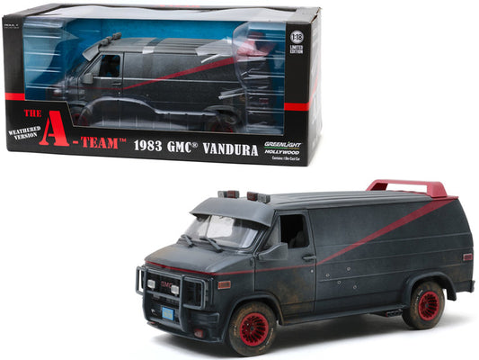 A diecast model of a 1983 GMC Vandura van from the A-Team TV series, predominantly black with weathering details and bullet holes, displayed alongside its packaging box.