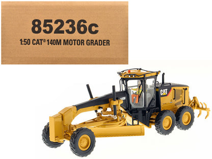 Model of a Caterpillar motor grader with packaging box in the background