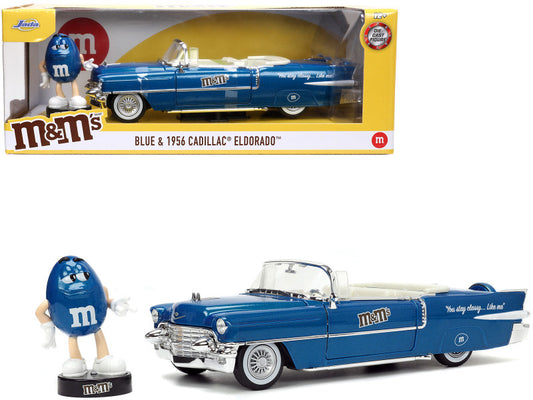 A 1:24 scale die cast metal model of a 1956 Cadillac Eldorado Convertible in blue color, accompanied by a blue M&M figure.